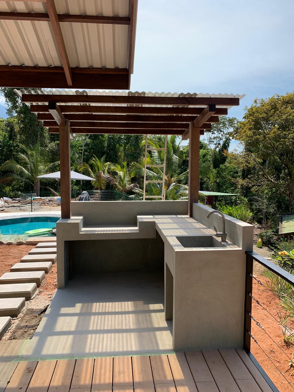 Outdoor kitchen and pergola beside a pool deck